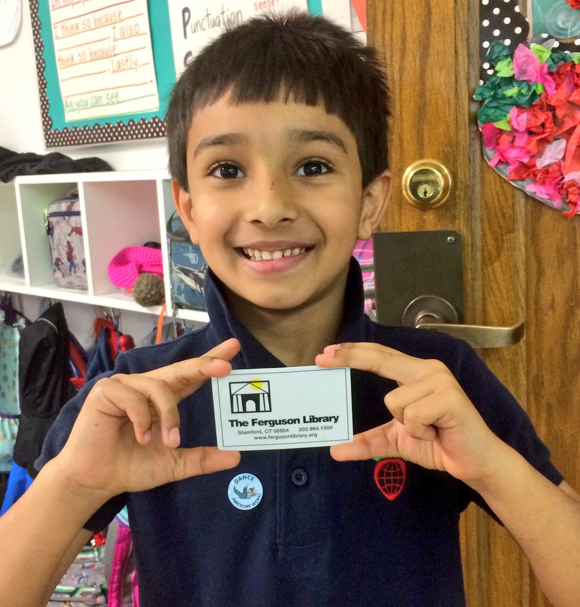 Young patron smiling and holding up his library card