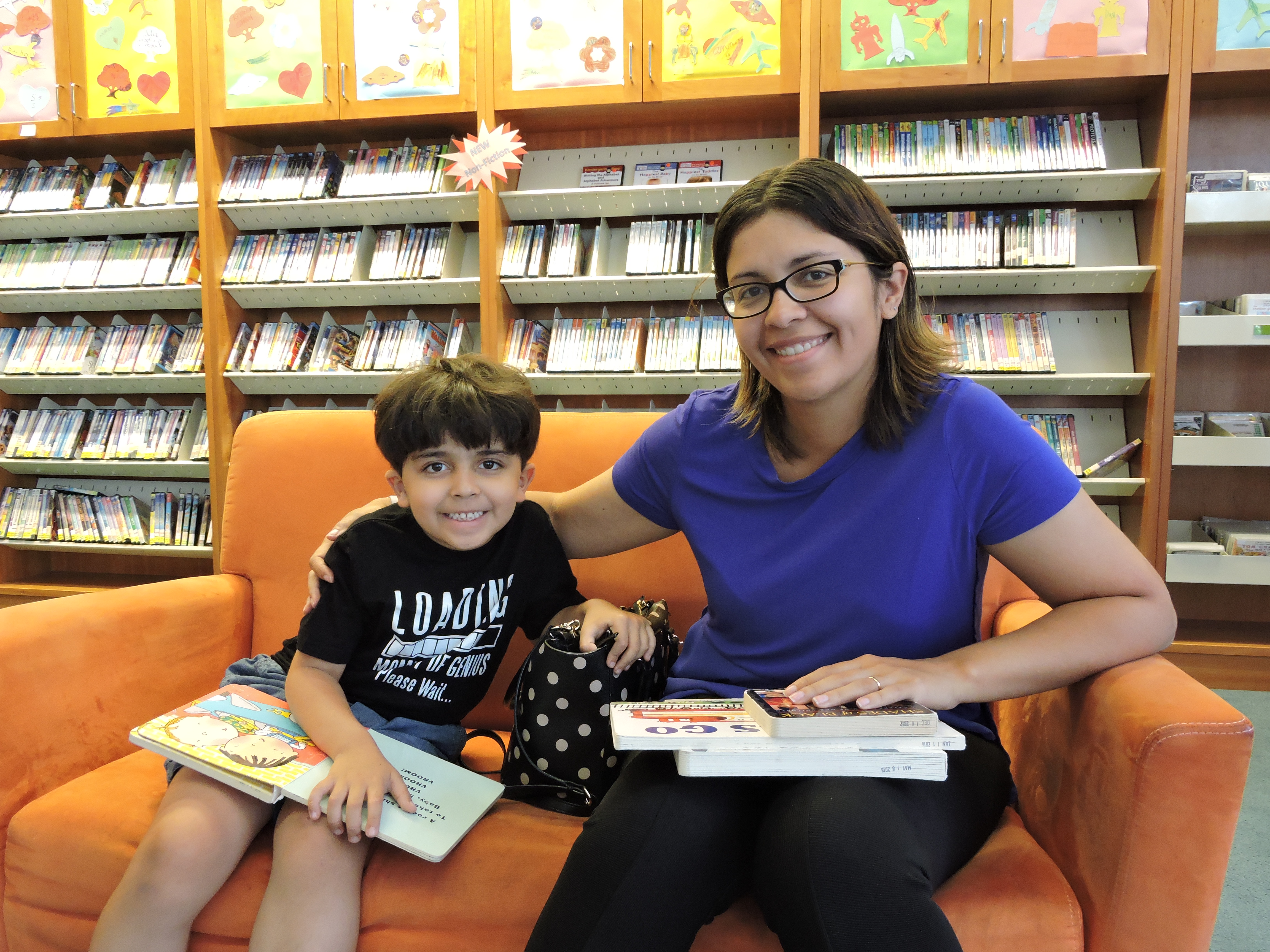 Little boy reading with mom in library