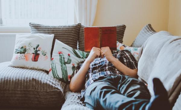 Man lying on couch reading
